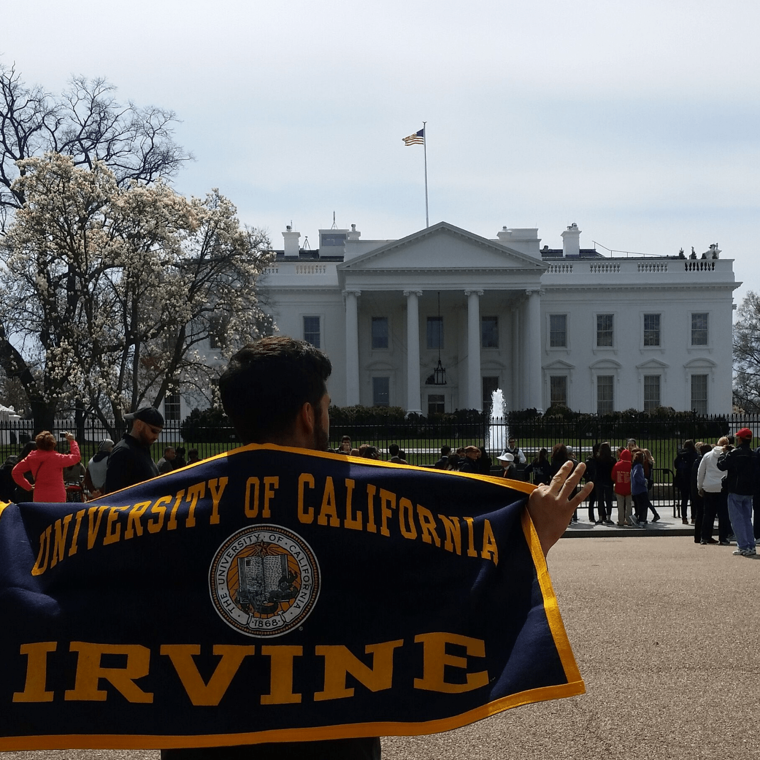 Student wearing a UC Irvine flag as a cape in front of the White House.